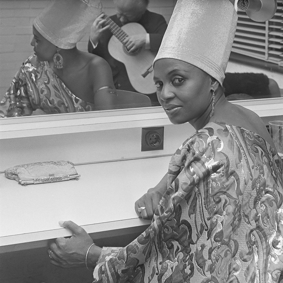 Miriam Makeba in her dressing room, wearing traditional headgear, 1969.